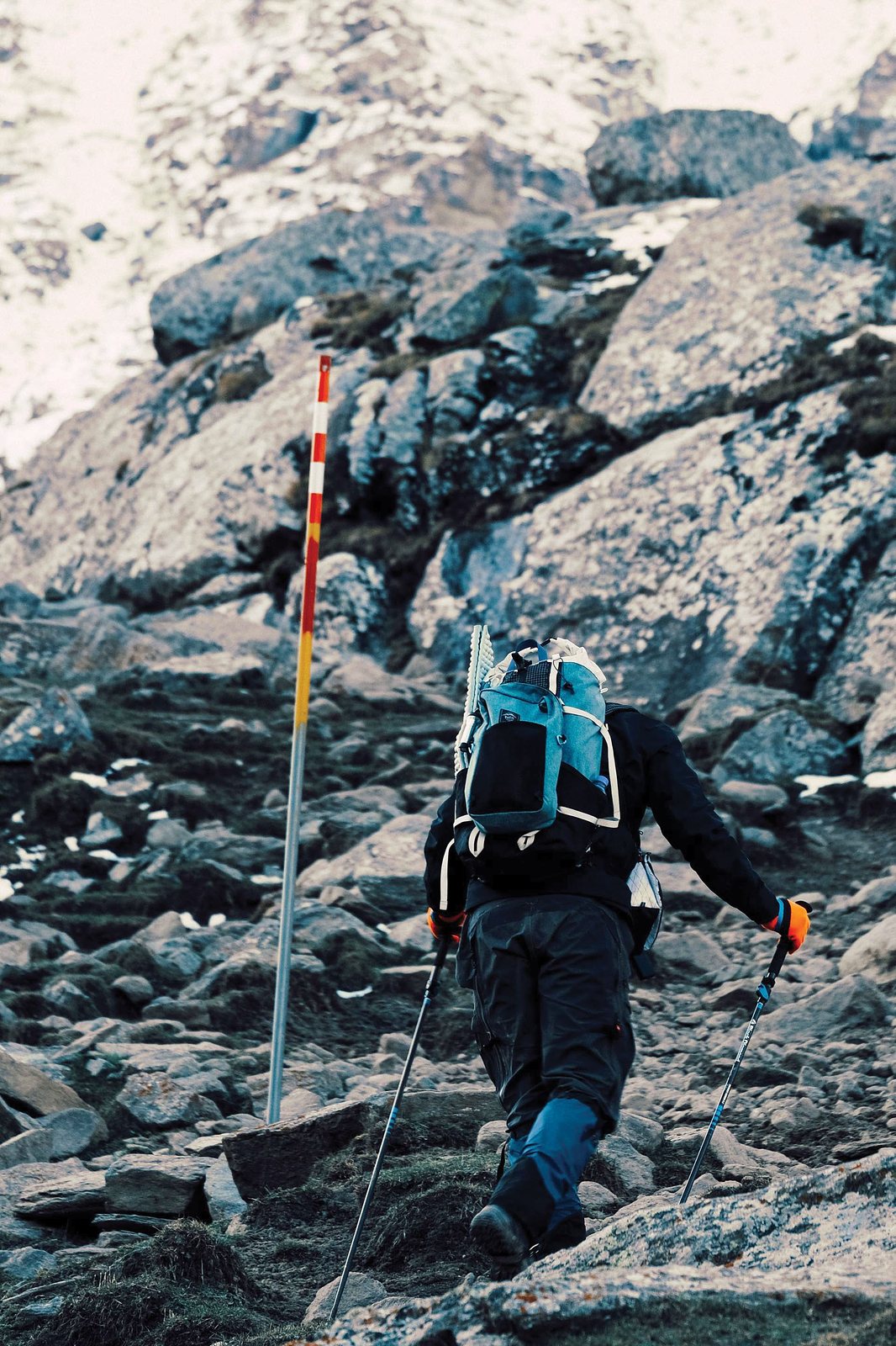 Hiker scaling a rocky mountain with backpack